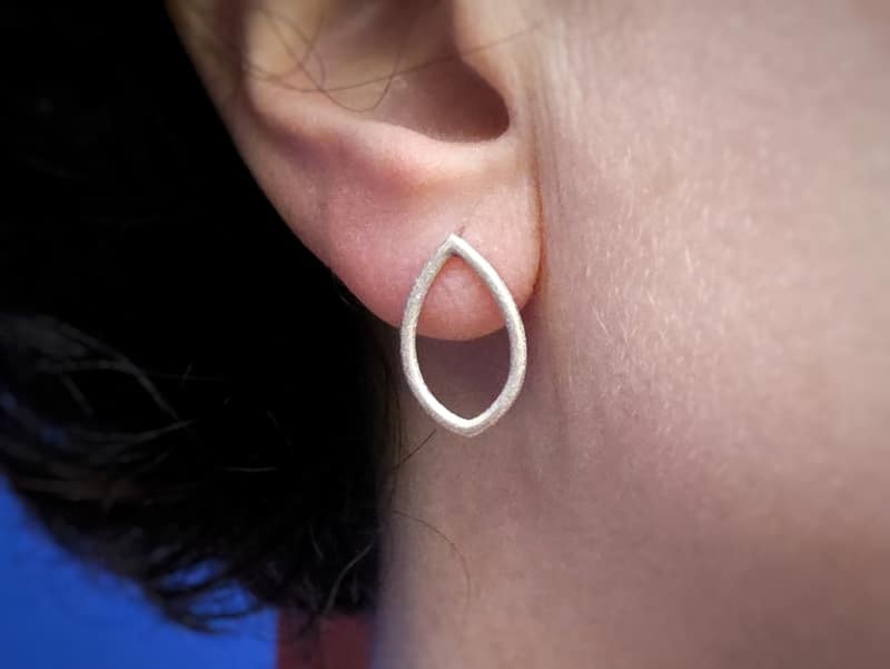 Zilveren oorbellen ‘Mackintosh’, speelse open vormen met een steker. Uit het Oogst atelier. Oorbellen op het oor gezien.